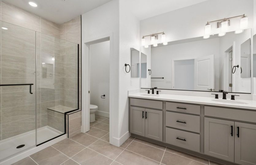 Owner's bathroom with glass walk-in shower and dual vanities