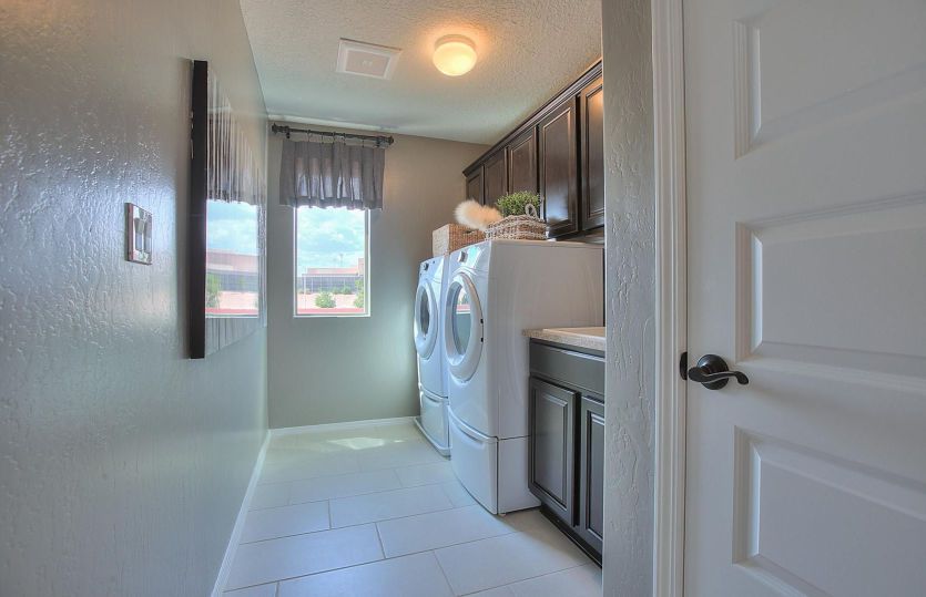 Roomy laundry room with extra storage cabinets added above and beside the washer/dryer.