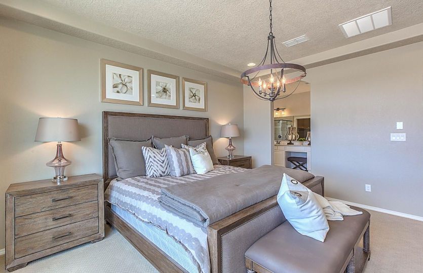 Owner's Suite in the Messina home design at Savio Ridge shown with a tray ceiling and decorative lig