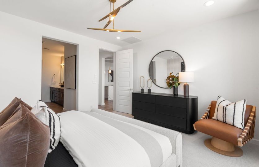 Owner's suite shown with a large bed and cozy accent chair.