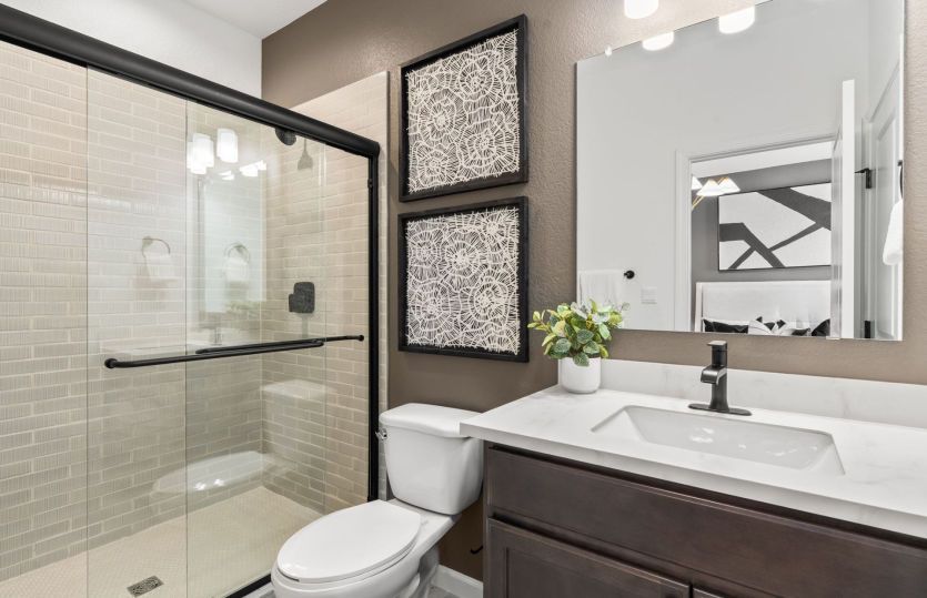 Elegant upstairs bath featuring dark cabinetry and a shower/tub combo.