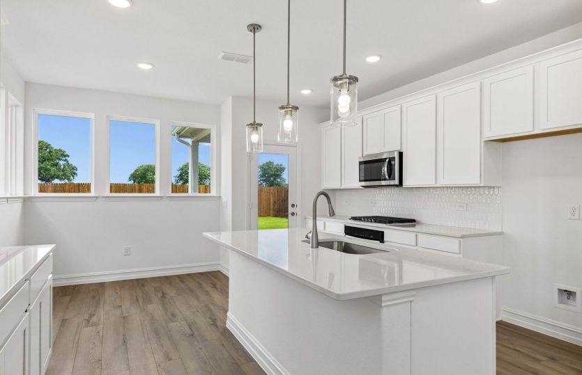 Beautiful pendent lighting and eat-in bartop island in kitchen *model representation