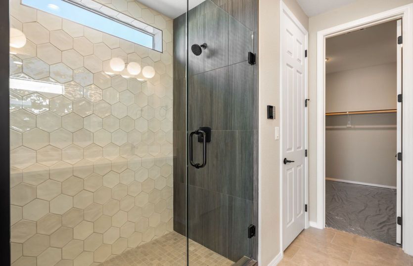 Spa-inspired owner's shower featuring designer tile, a frameless glass enclosure, and built-in bench