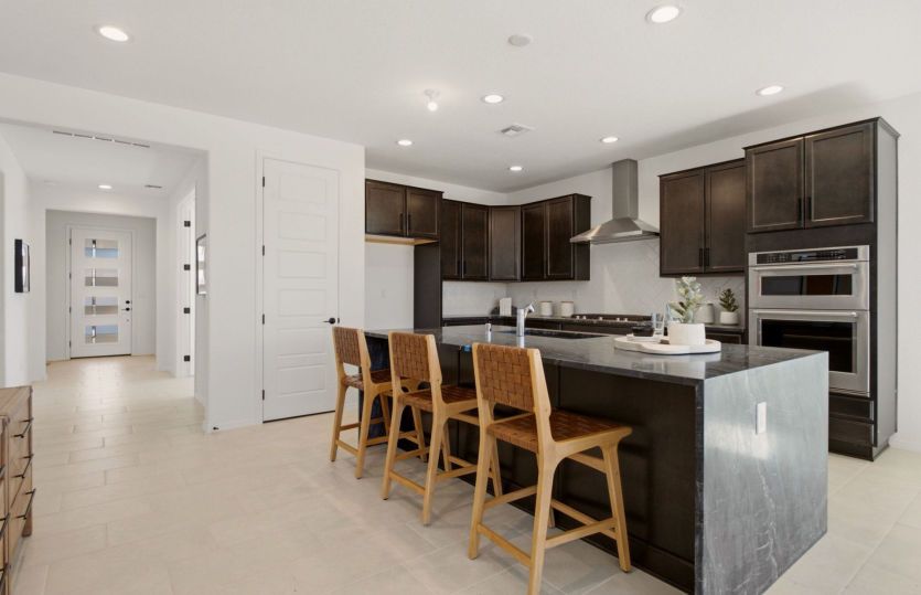 Designer kitchen showcasing a dramatic waterfall island, stainless steel appliances, and abundant cabinetry