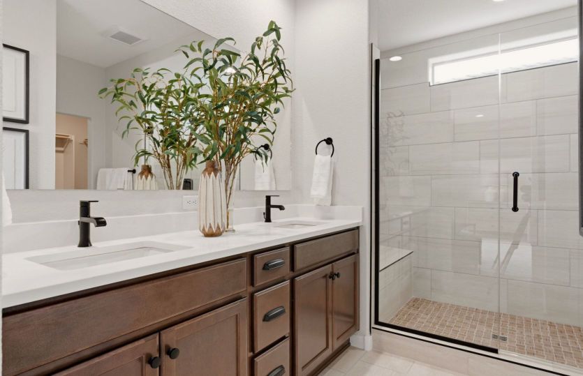The owner's bath shown with a dual sink vanity and a beautifully tiled shower.