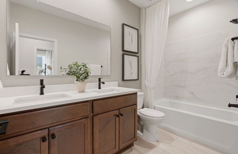 Secondary bathroom shown with a dual sink vanity and a tiled walk-in shower.