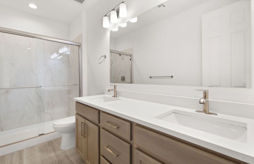 Secondary bathroom with dual sinks and framed glass shower