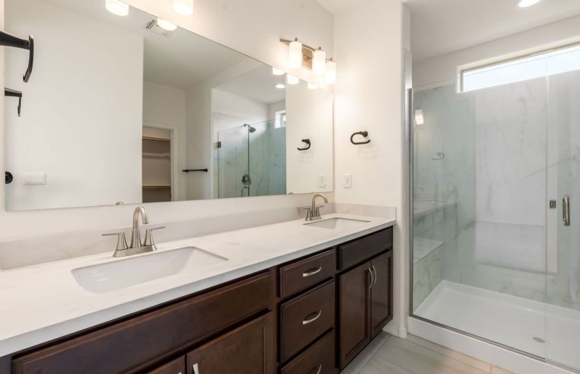 Luxurious owner's bath with dual sinks and frameless glass shower