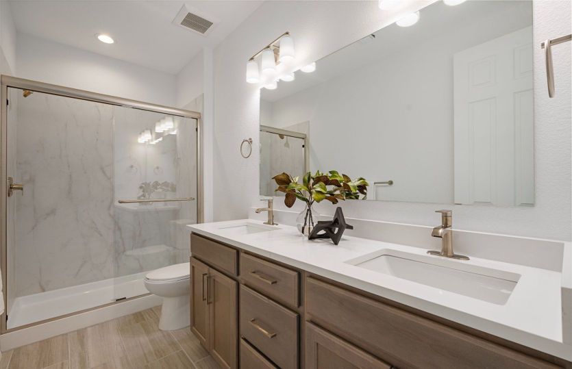 Secondary bathroom with dual sinks and framed glass shower