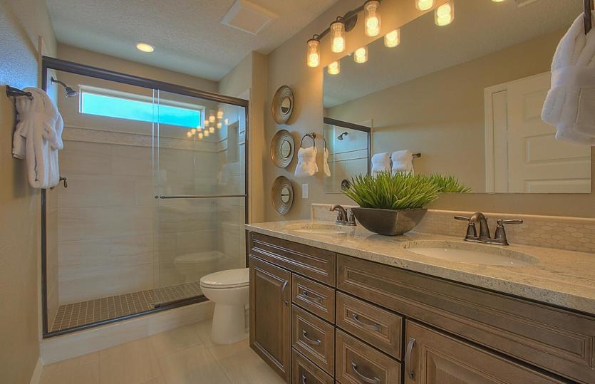 Second floor guest bathroom with bronze touches like bath hardware, framed shower and vanity lightin