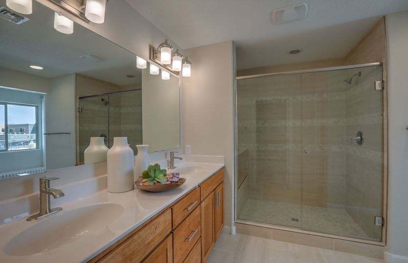 The owner's suite bath offers dual sinks with overhead lighting, cabinet space and a spacious tile s