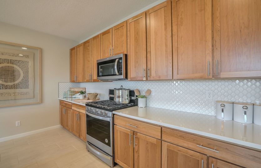 A look at the Quartz countertop and white tile backsplash plus stainless steel appliances in the kit