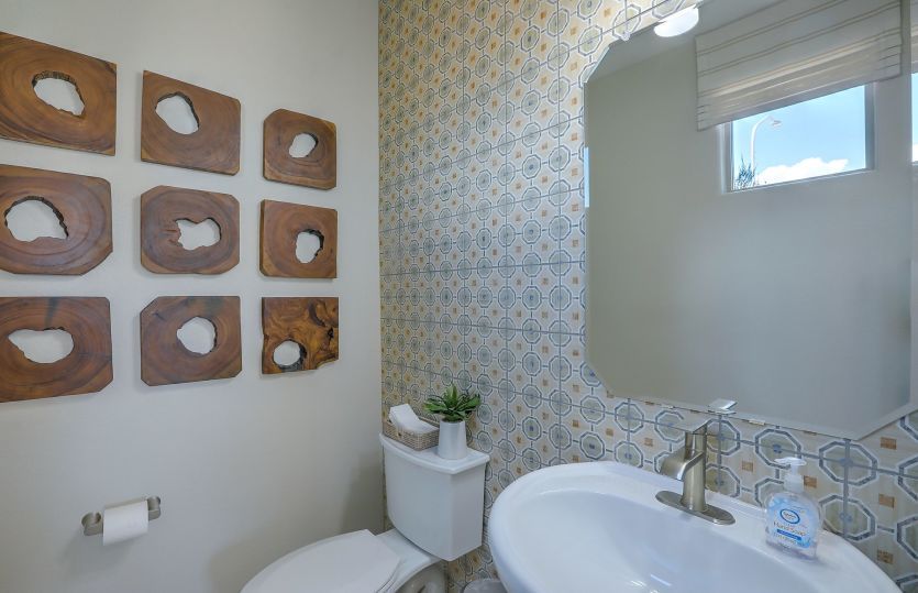 First floor powder bath for guests detailed with a tile accent wall, pedestal sink and octagon mirro