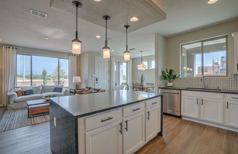 A granite kitchen island with waterfall-edge detail and pendant lighting overlooks the gathering roo