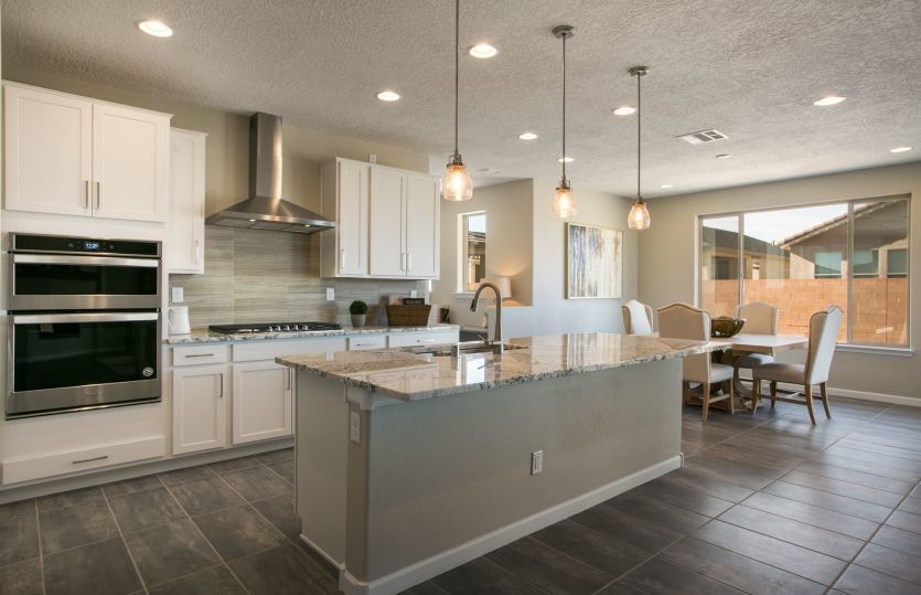 A designer Chef kitchen layout with white cabinetry, built-in appliances and pendant lighting.