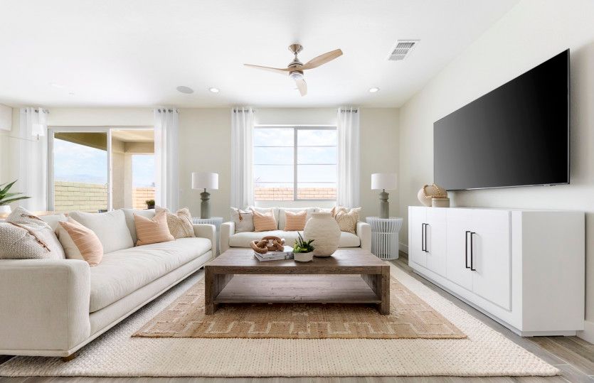 Spacious gathering room well-lit by large windows and sliding glass doors to the backyard.