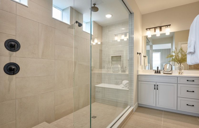 The walk-in shower features beautiful tile accents and a glass door.