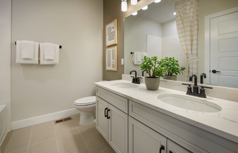 Secondary bathroom features a dual sink vanity and a shower/tub combo.