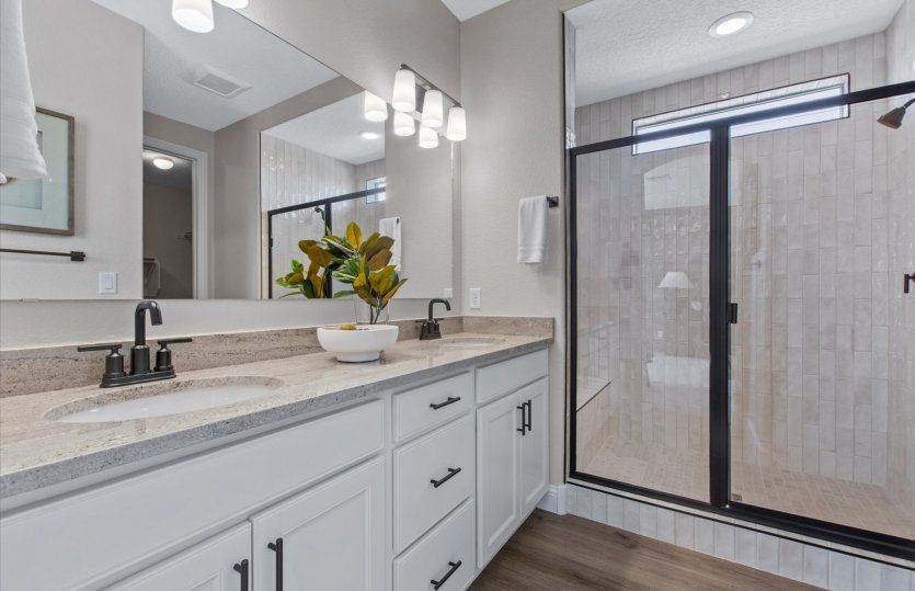 The owner's bath shown with a dual sink vanity and a beautifully tiled shower.