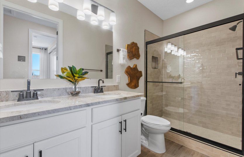 Secondary bathroom shown with a dual sink vanity and a tiled walk-in shower.