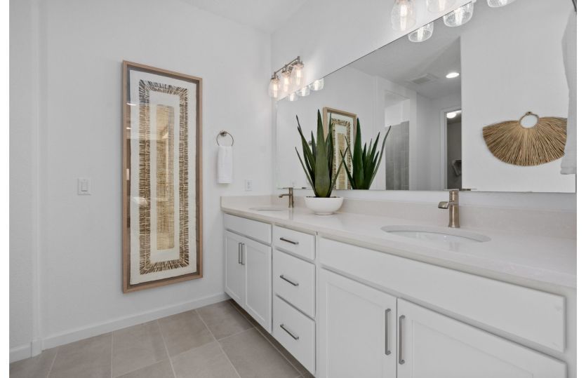 Owner's bath with double vanities and modern accents complemented by white cabinets.
