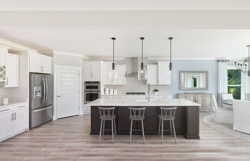 Large kitchen area with an island centered underneath pendant lighting.