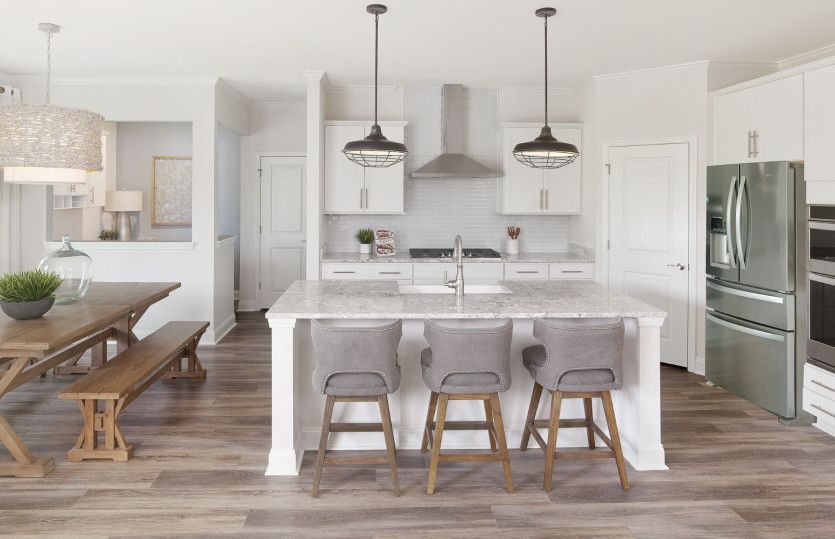 A bright, gourmet kitchen equipped with pendant lighting fixtures and beautiful hardwood flooring.