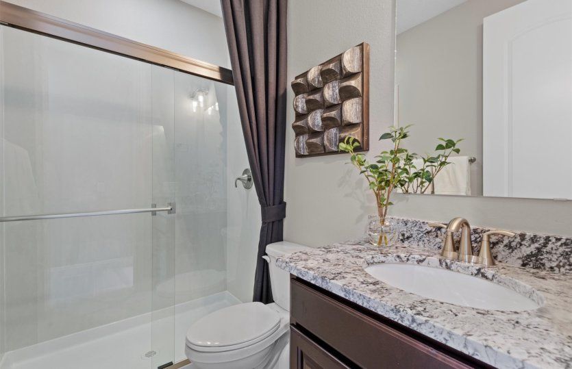 Downstairs guest bath featuring beautiful countertops and a shower/tub combo.