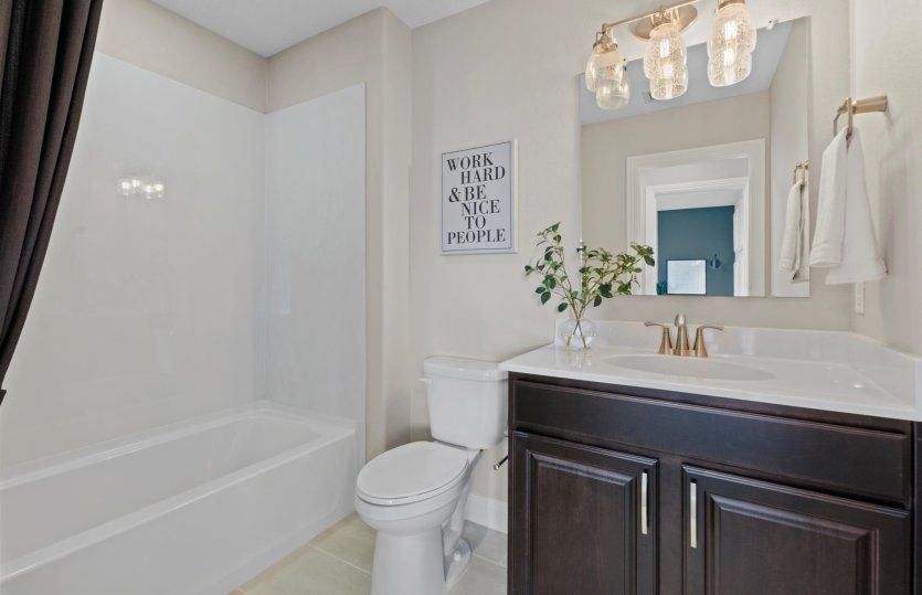 Elegant upstairs bath featuring dark cabinetry and a shower/tub combo.
