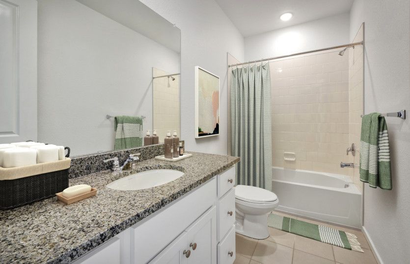 The secondary bathroom features granite countertops and a shower/tub combo.
