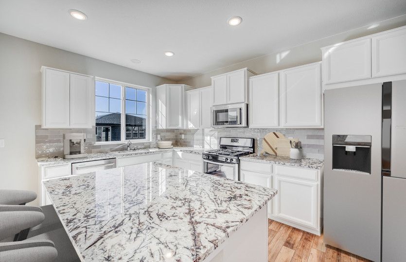 The kitchen features a spacious island, ample cabinet space, and can be designed with finishes like