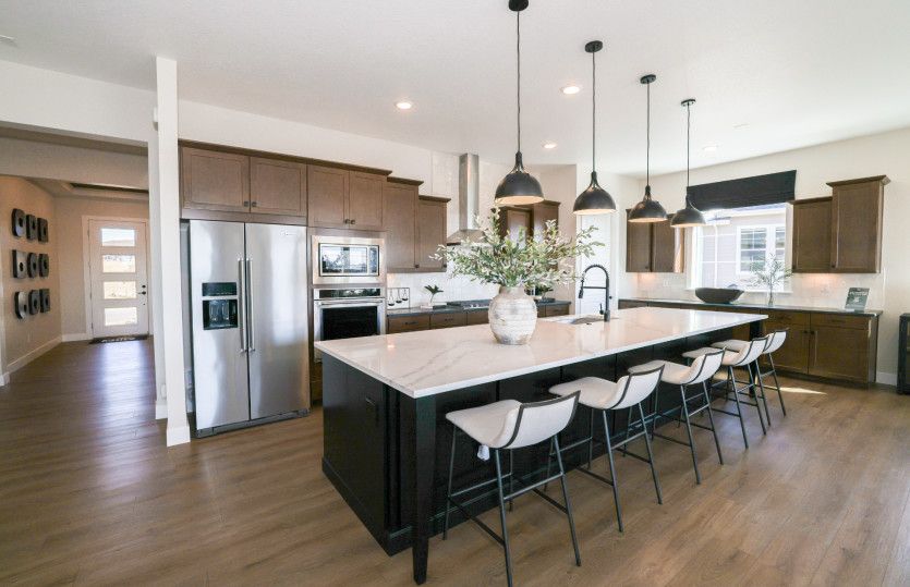 Enjoy a huge kitchen island shown here with accent pendants and stylish, white granite.