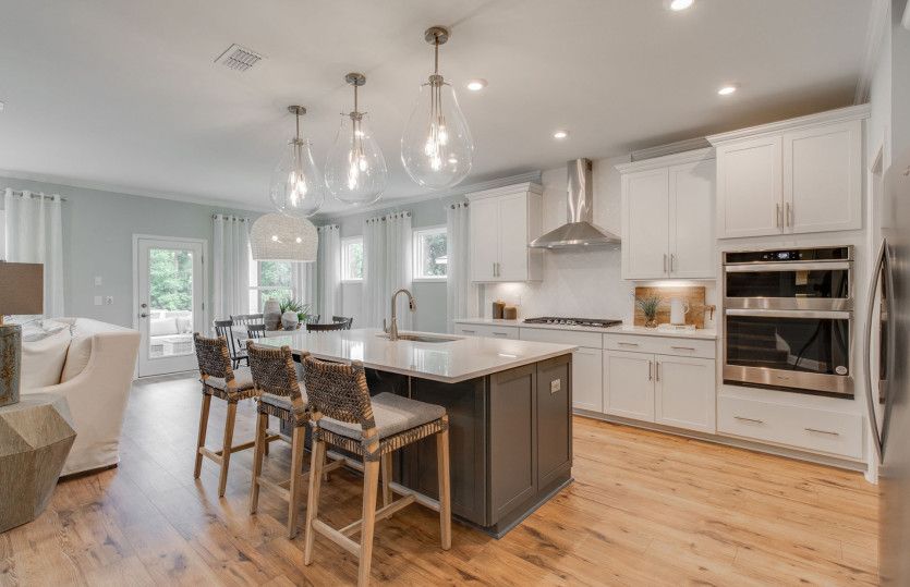 Luxurious Kitchen with stainless steel appliances, bright white tile backsplash, and unique pendant