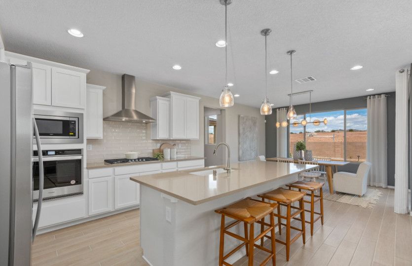 A designer Chef kitchen layout with white cabinetry, built-in appliances and pendant lighting.