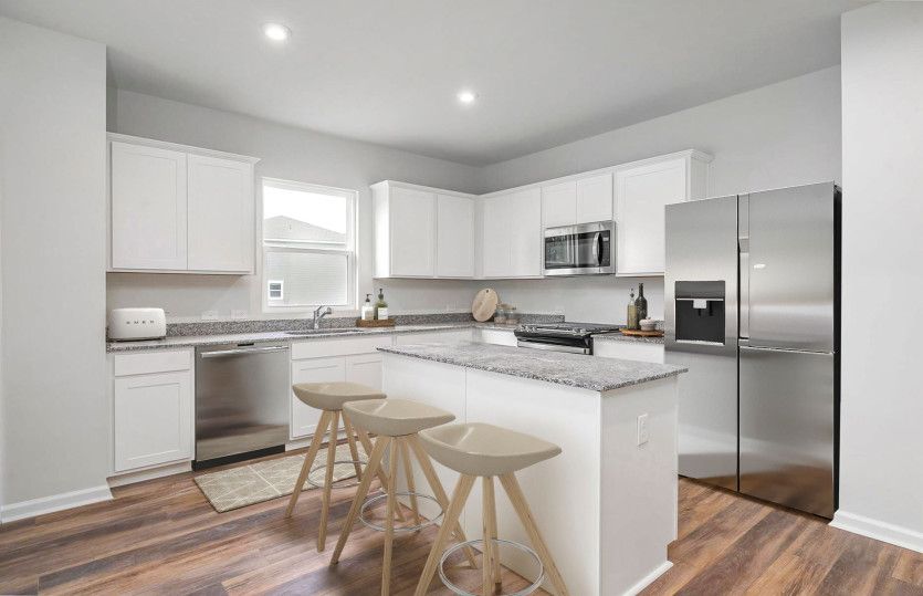The open floorplan concept is ideal for preparing meals in the Kitchen with bright white cabinets.