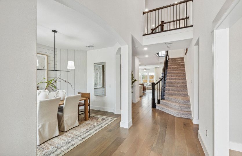Welcoming entry into two-story ceilings and staircase*model representation