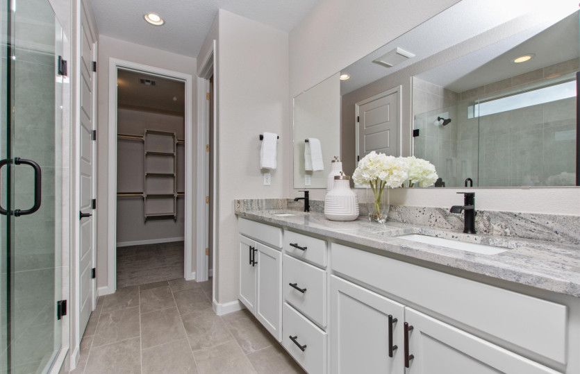 Luxurious owner's bath with a dual sink vanity on granite countertops and white cabinets.