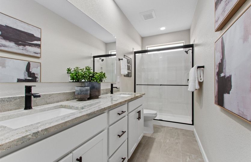 The secondary bath upstairs includes a walk-in shower and a dual sink vanity.