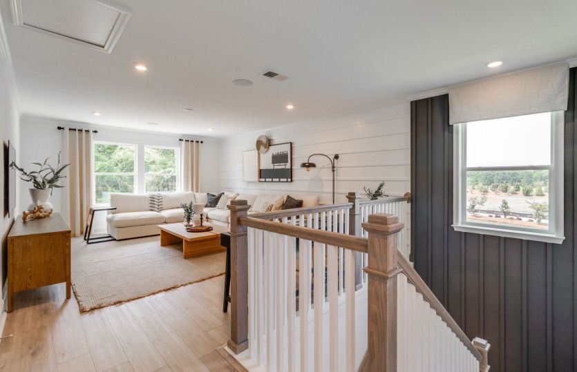 An expansive upstairs loft bathed in abundant natural light offers an airy retreat for various activ