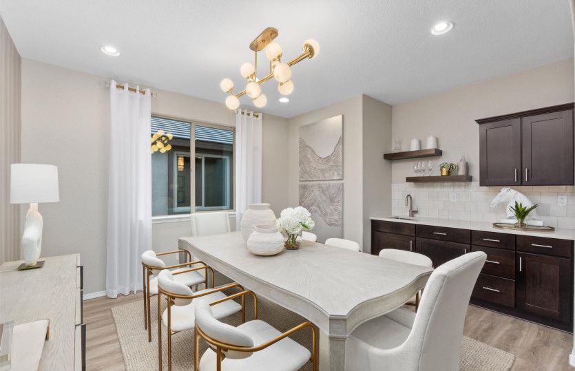 Dining room with decorative light, and a bar with extra cabinets for storage.