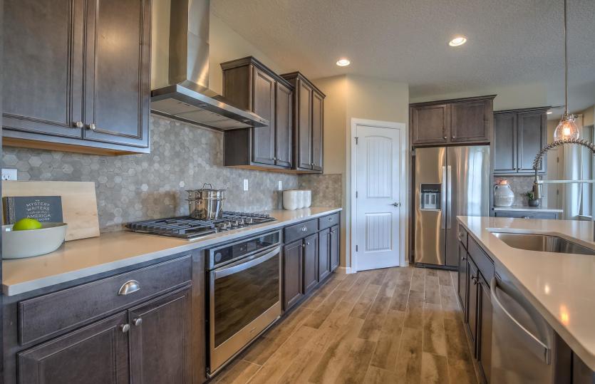 Chef kitchen with staggered cabinets, quartz countertops and stainless steel appliances
