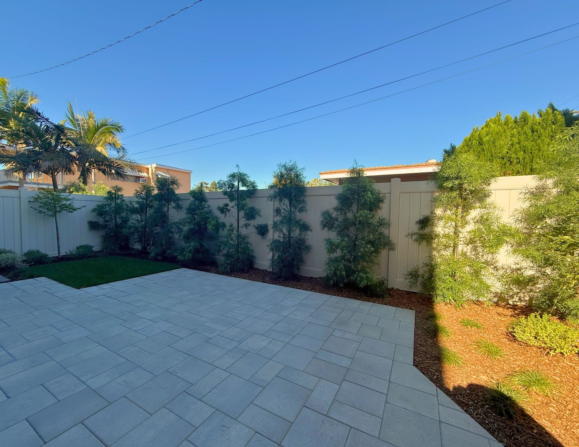 Outdoor patio with landscaped trees and vinyl fencing