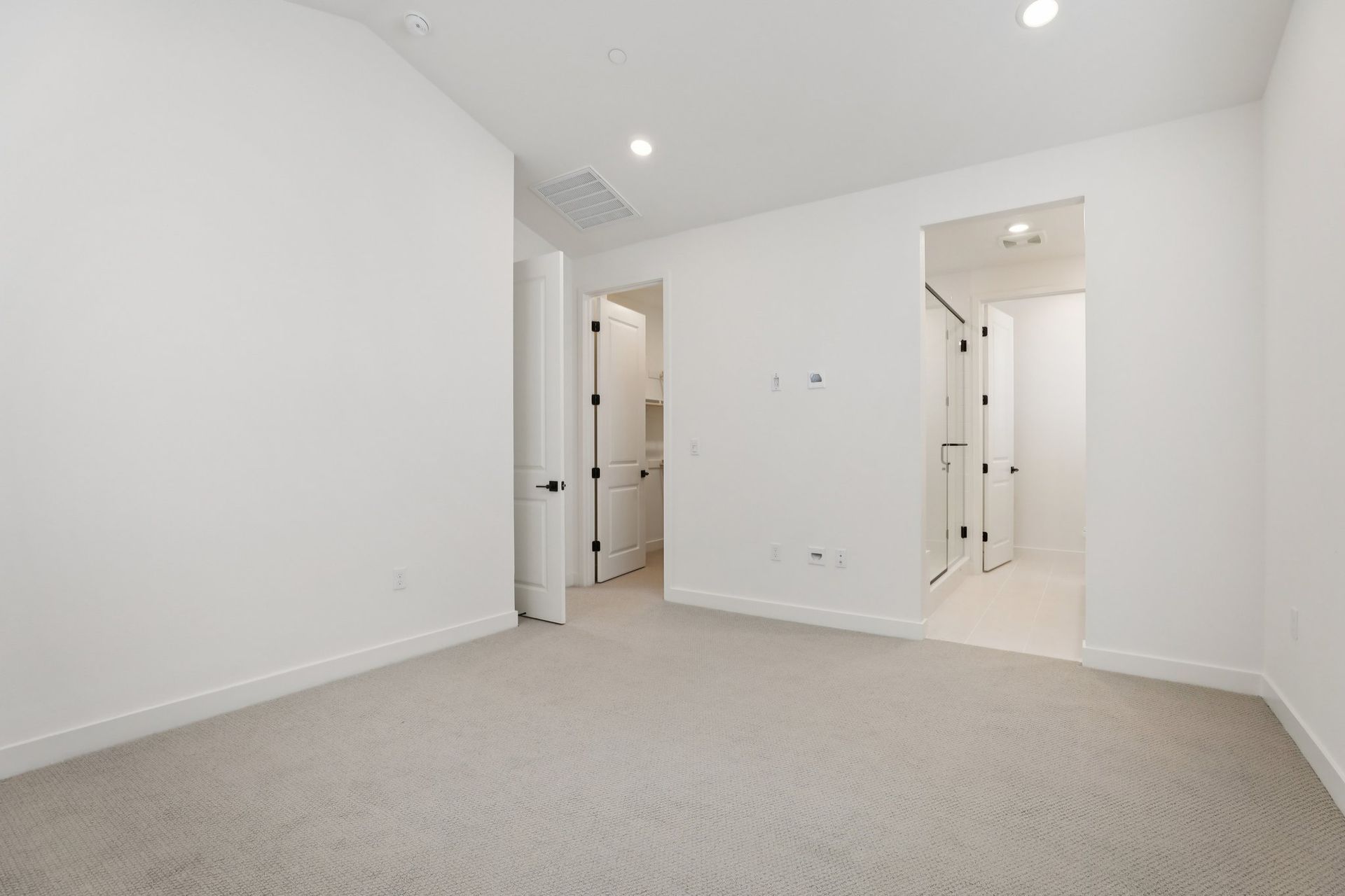 Primary bedroom with vaulted ceiling and upgraded flooring