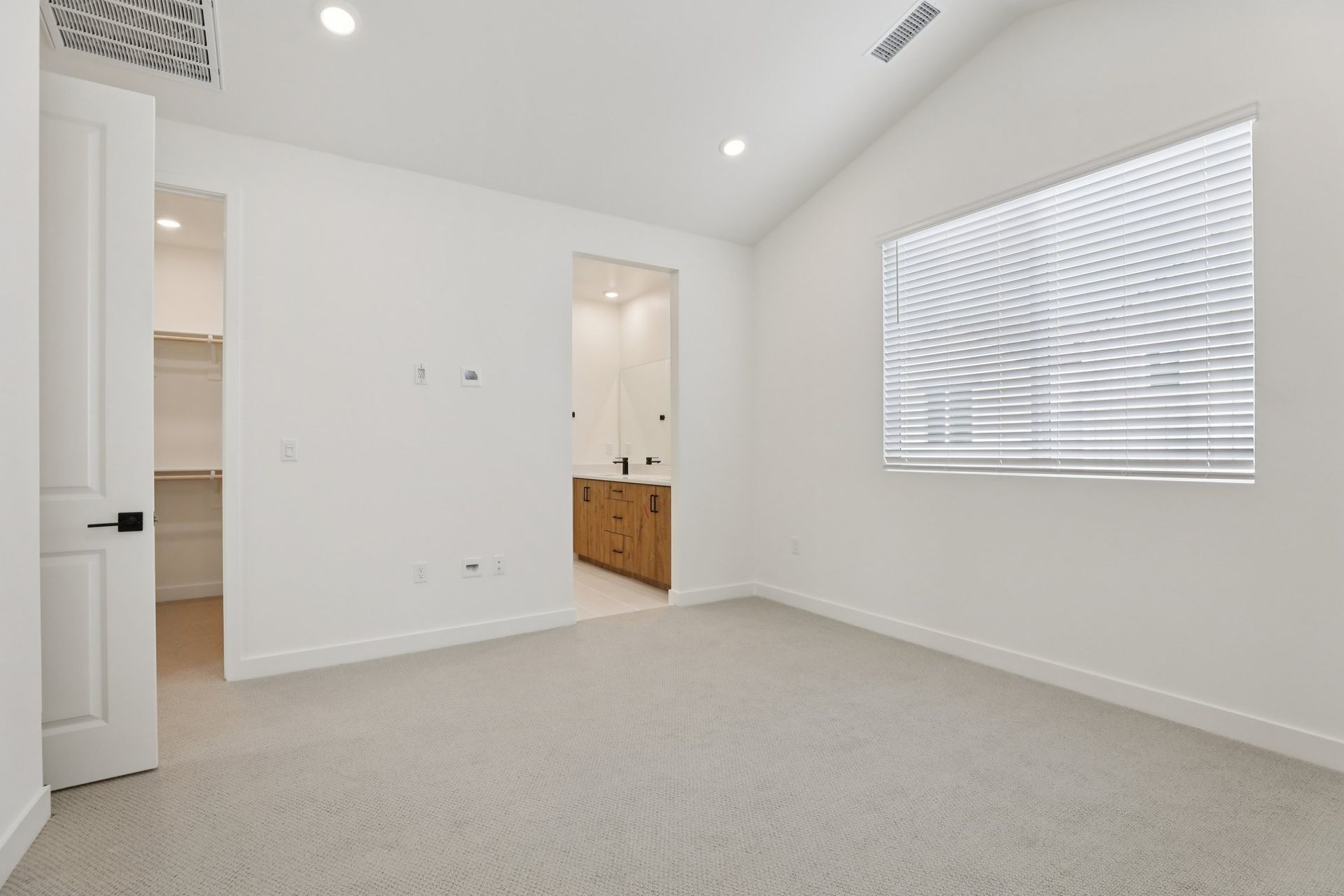 Primary bedroom with vaulted ceiling and upgraded flooring