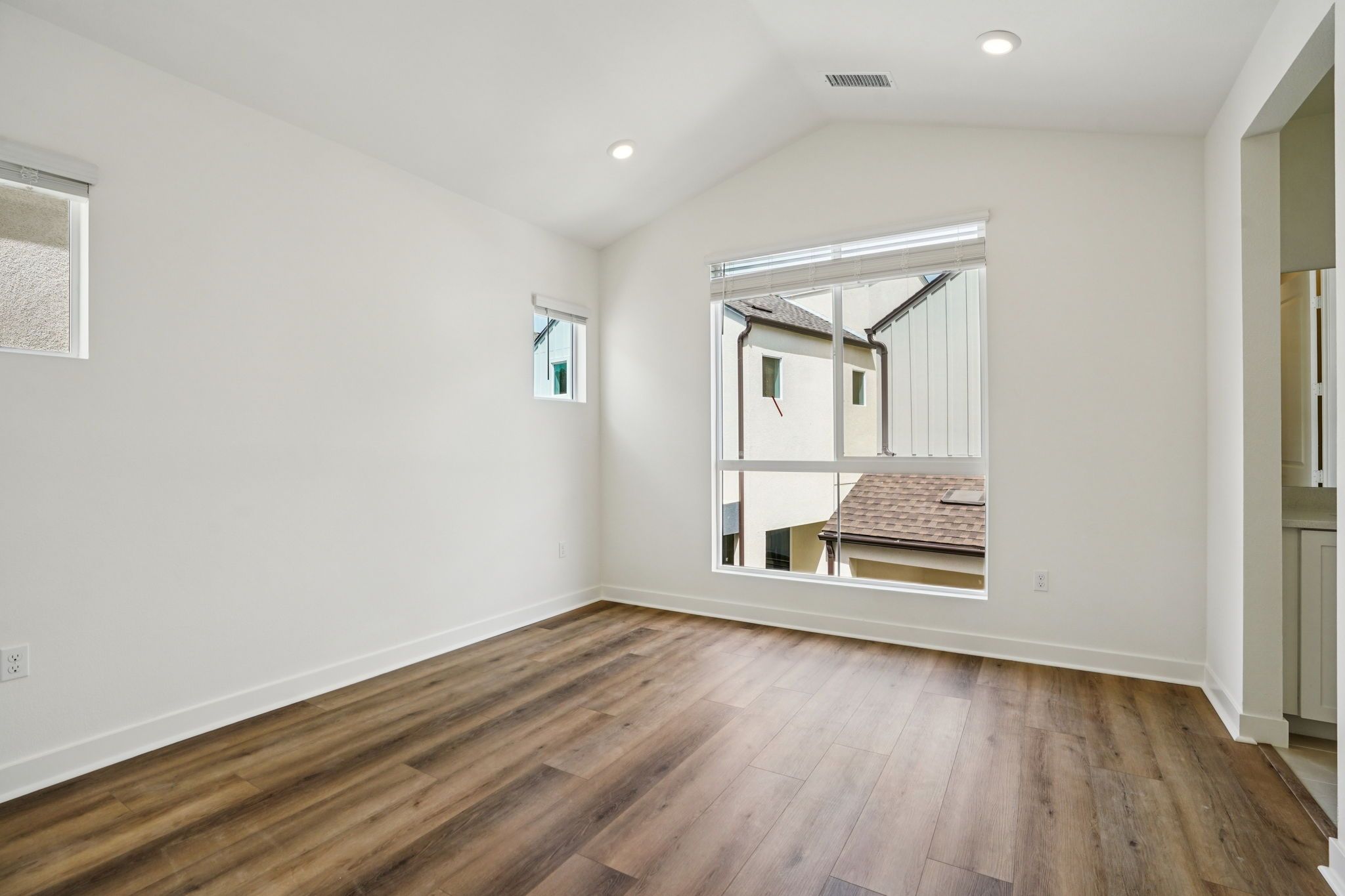 Open primary bedroom with a bright, tall window