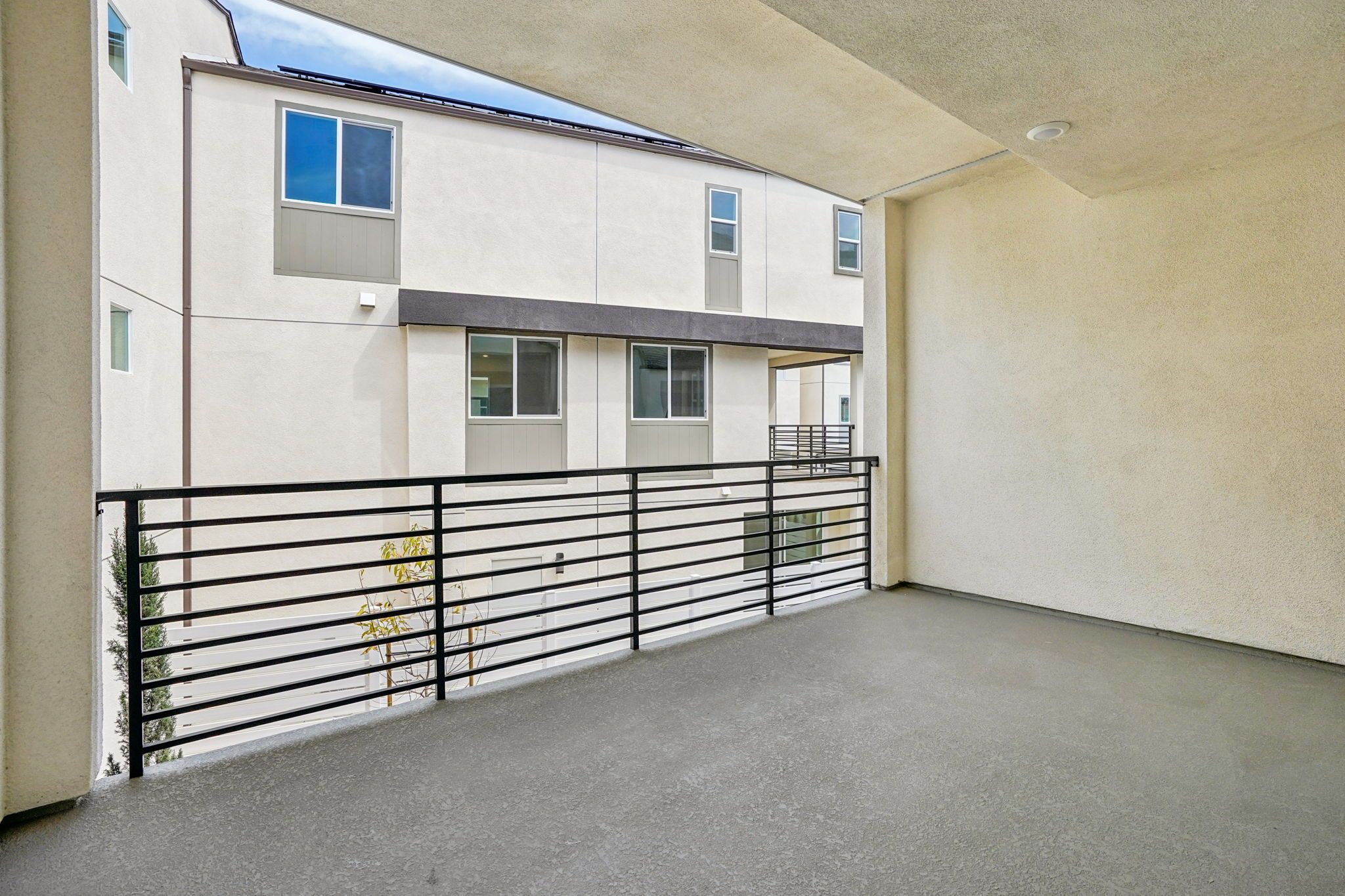 Covered deck with seating area and sliding doors offering neighborhood views