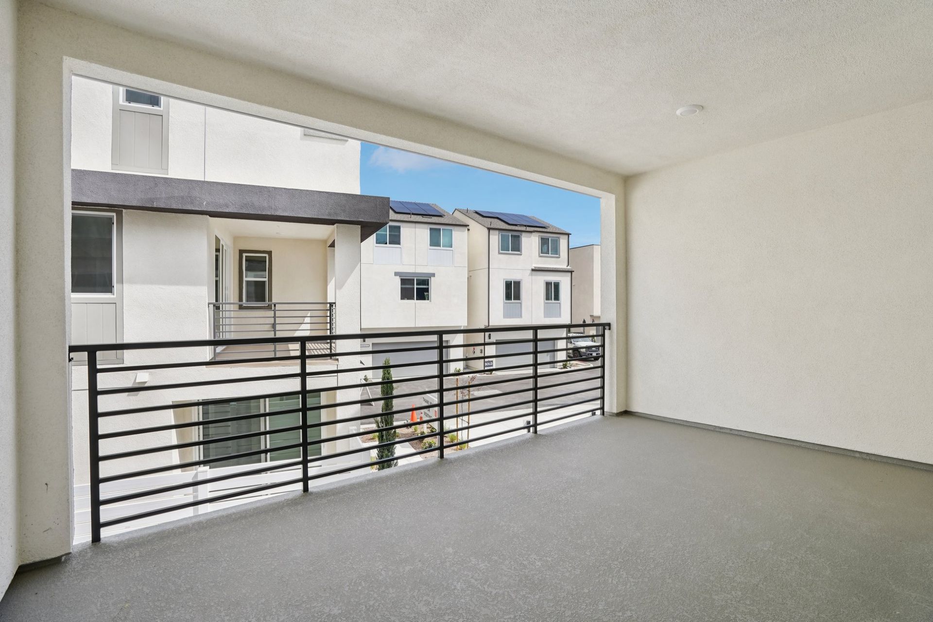 Covered deck with seating area and sliding doors offering neighborhood views