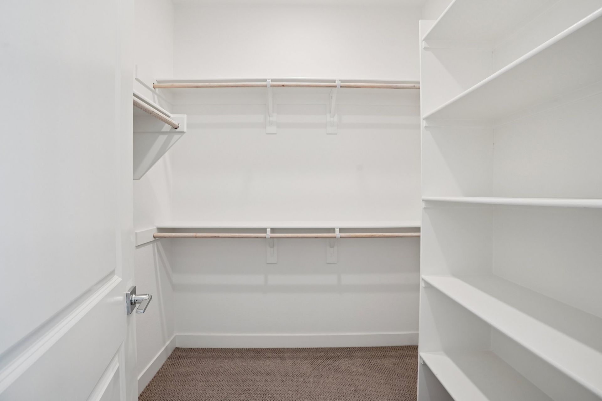 Large primary walk-in closet with ample shelving and hanging space.