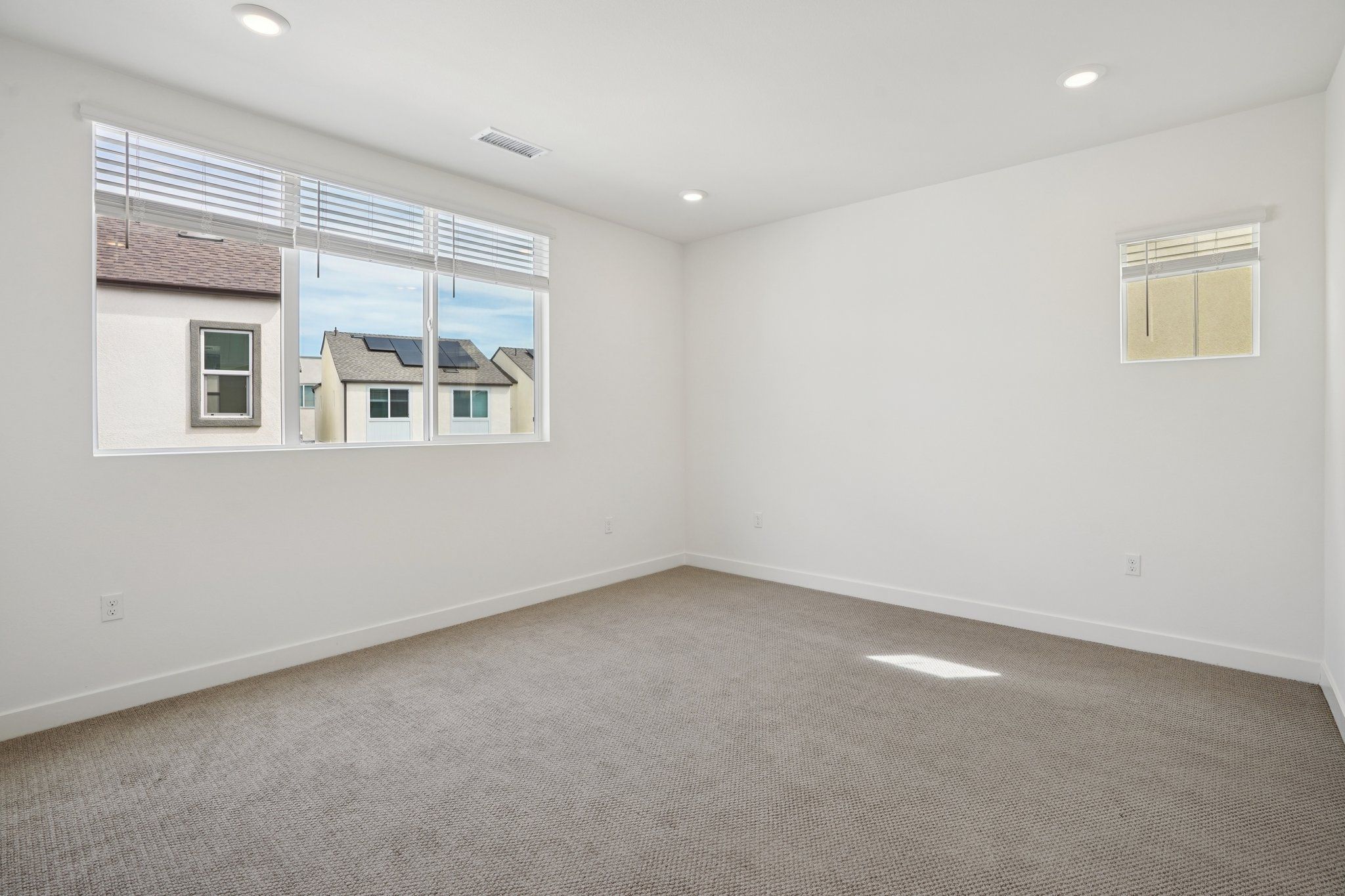 Open primary bedroom with a bright, tall window