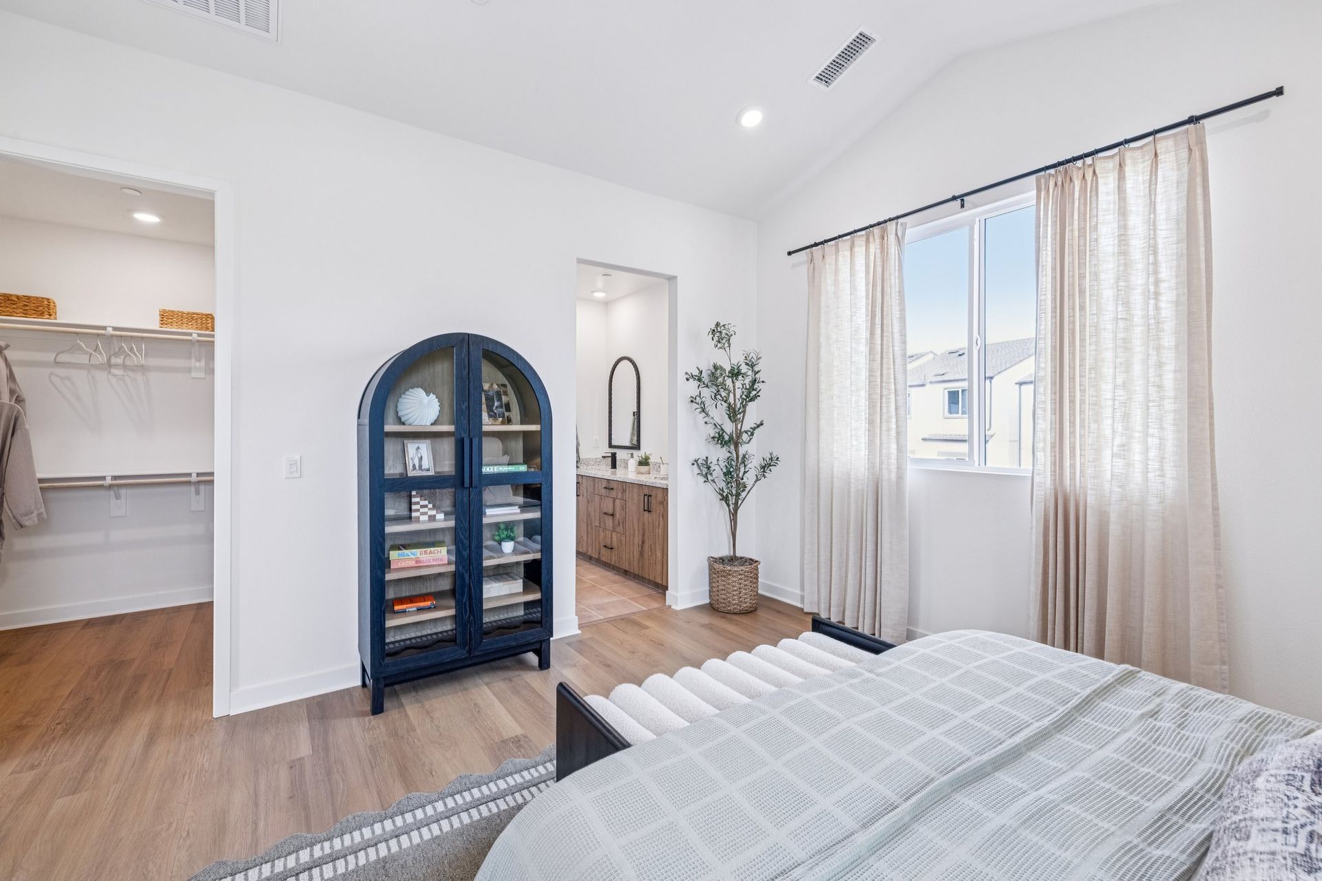 Model home large primary bedroom with en-suite bathroom and vaulted ceilings